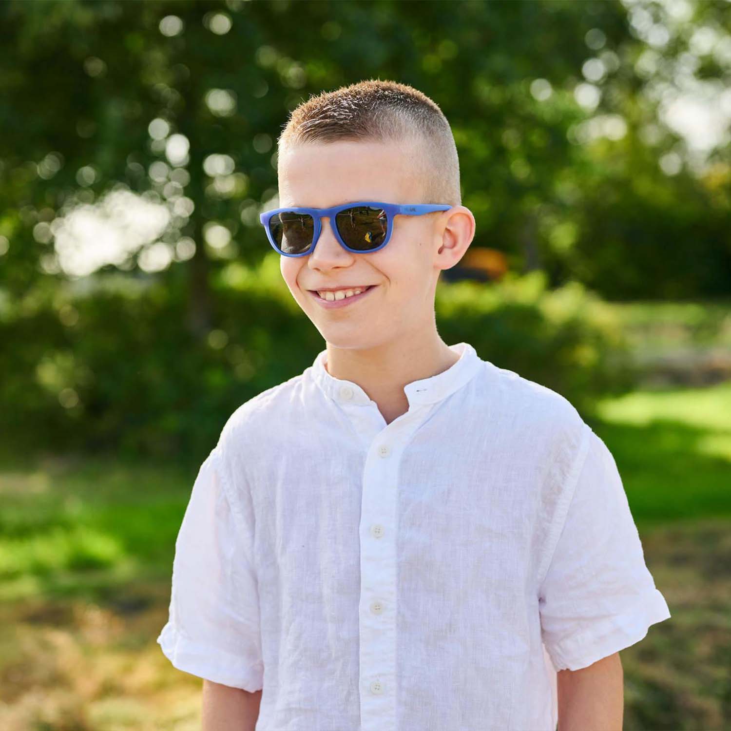 Milo & Me Kindersonnenbrille Dominique Dunkelblau Denim Hellblau Junge mit dunkelblondes kurzem Haar und weißem Hemd  10 - 12 Jährige 